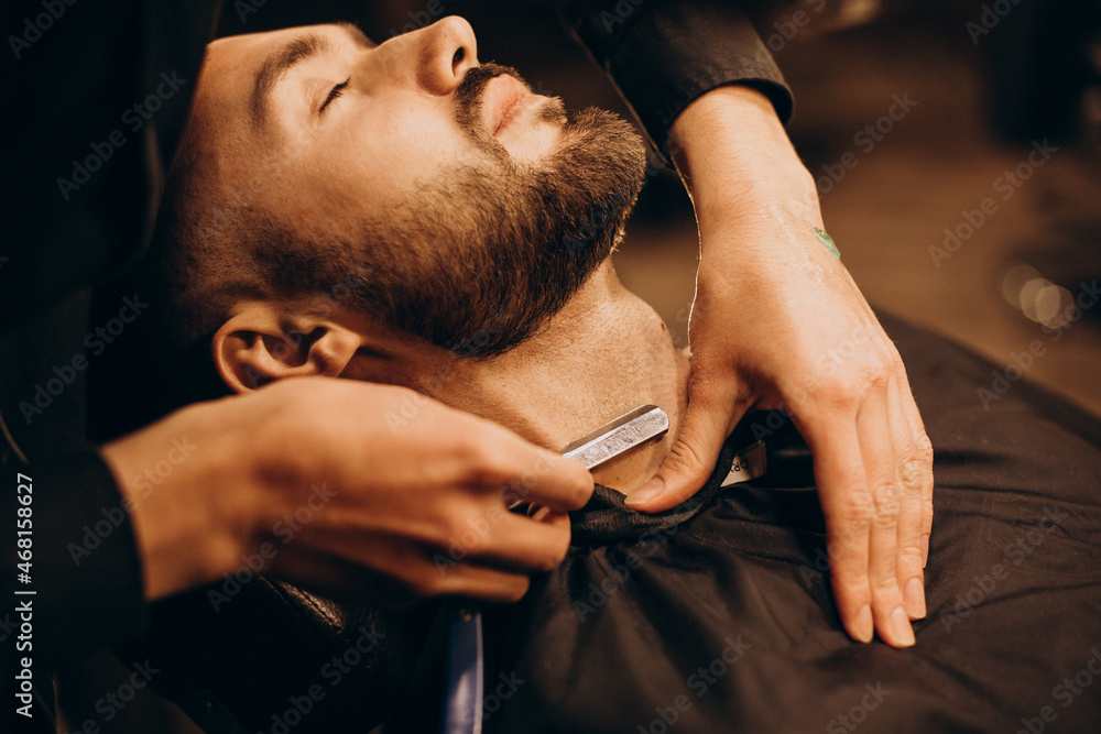 Handsome man shaving beard at barbershop
