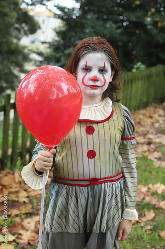 niño disfrazado de payaso malvado con globo rojo photo