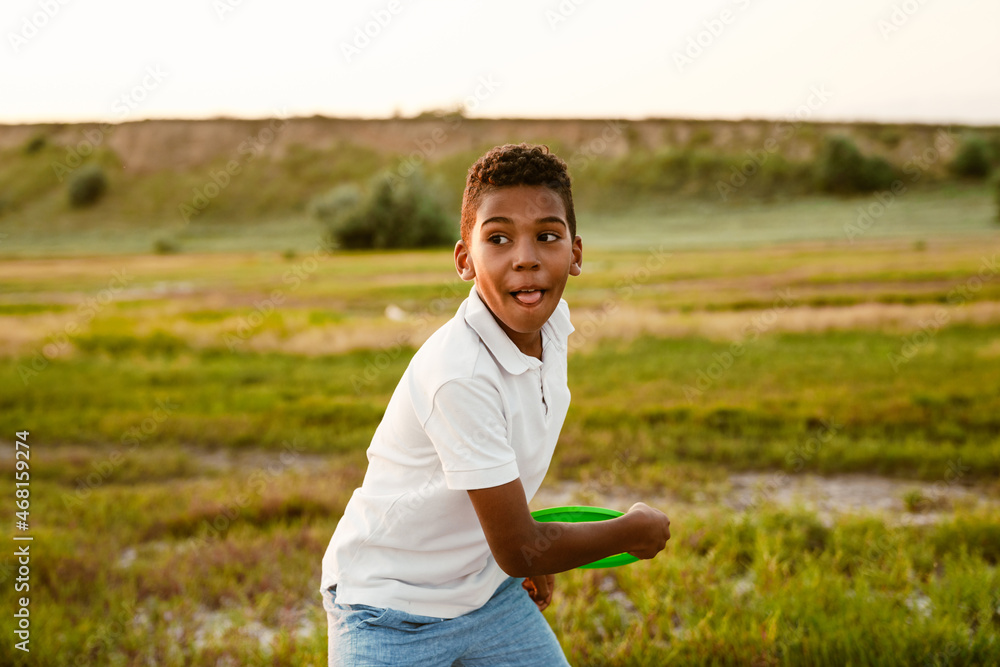 Black boy wearing white shirt playing with frisbee Black boy wearing white shirt playing with frisbee