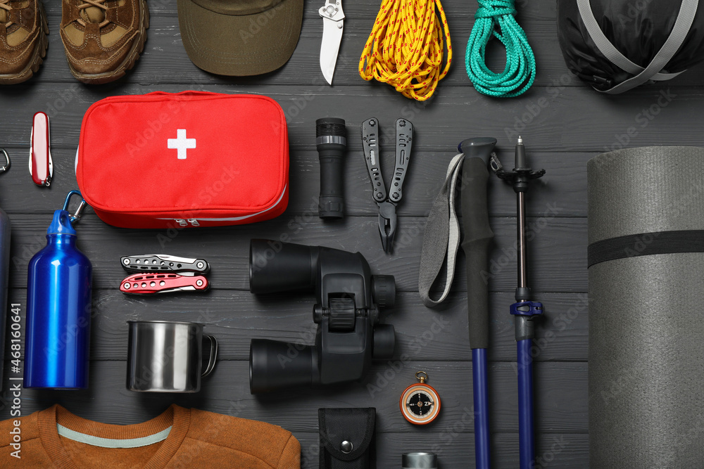Flat lay composition with trekking poles and other hiking equipment on dark grey wooden background Flat lay composition with trekking poles and other hiking equipment on dark grey wooden background