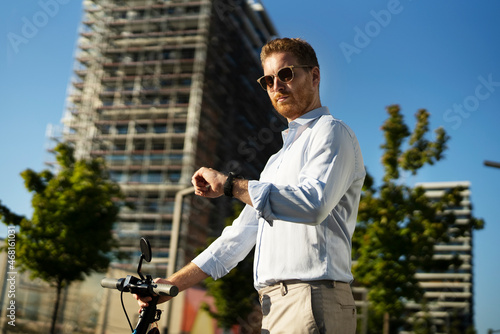 Young stylish businessman with e-scooter. Portrait of handsome man outdoors