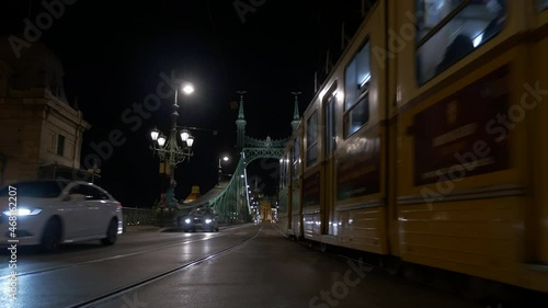 Clean shot of tram in the hungarian capital passing the liberty bridge at night in 4K resolution
