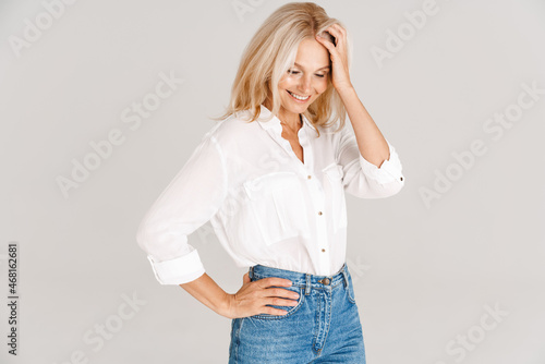 Mature blonde woman wearing shirt smiling and looking downward