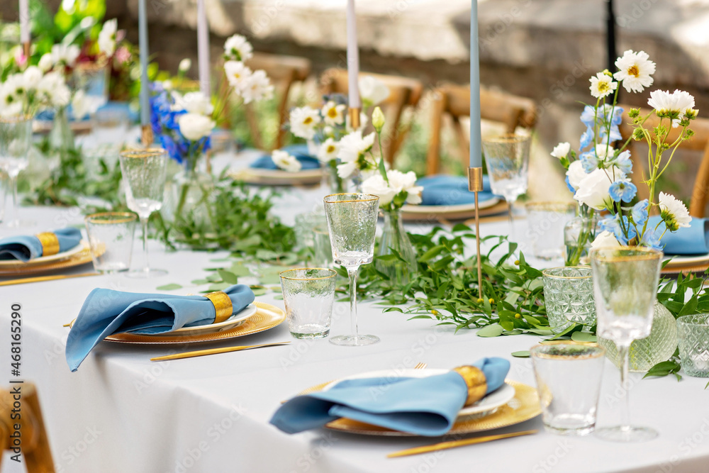Banquet wedding table setting with blue napkins, gold cutlery, crystal,  fresh flowers and candles. Wedding decorations. Soft selective focus. Stock  Photo | Adobe Stock