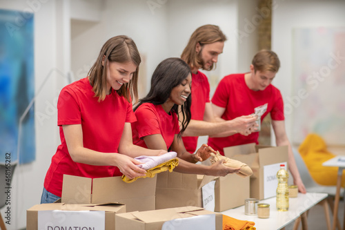 Young peeple in red packing the cardboards with humanitarian help photo