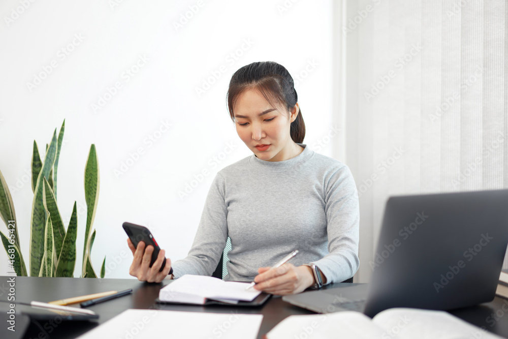 Office work concept a female officer using a mobile phone to check meeting agenda for tomorrow