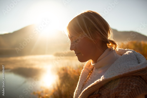the portrait of the woman against the lake , sun and mountain