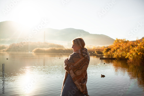 Back view of woman dressed in poncho and look to the lake, enjoy life, happy in moment