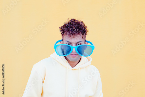 Funny picture : Latin guy with big glasses looking at camera with yellow background © Clara