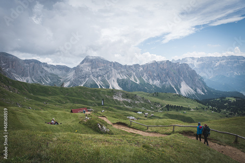 Girls hiking in dolomites. Green grass field in Dolomites. Trentino Alto Adige, Dolomites Alps, South Tyrol, Italy.