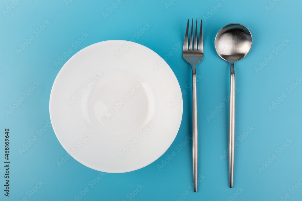 Empty plate with fork and spoon on blue background. Flat lay Dishes for breakfast, lunch or dinner Mock up Empty plate with fork and spoon on blue background. Flat lay Dishes for breakfast, lunch or dinner Mock up