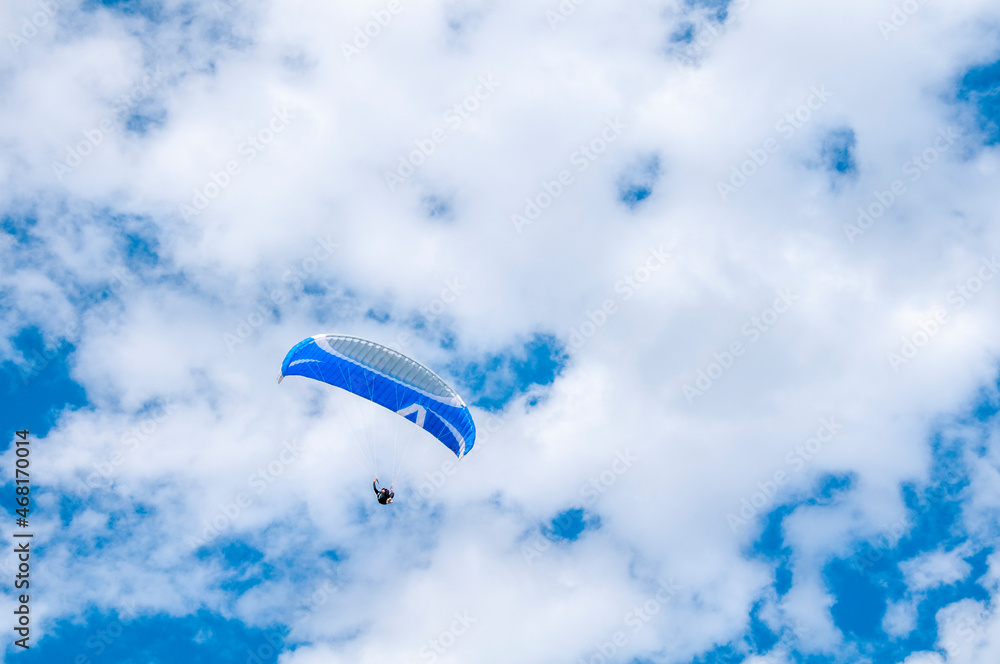Obraz premium Paraglider flying into the sky with clouds on a sunny day.