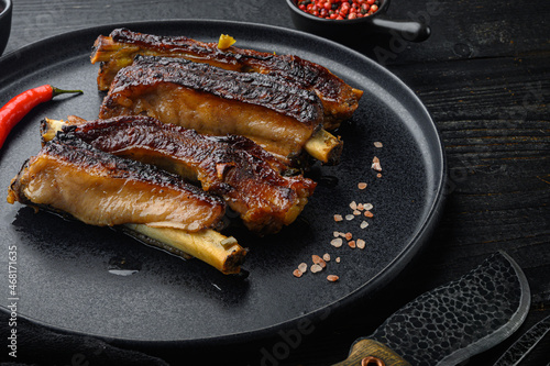 Barbecue pork spare ribs, on plate, on black wooden table background