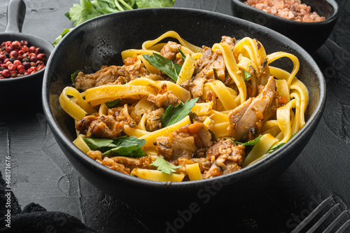 Pasta with rosemary rabbit stew, in bowl, on black stone background
