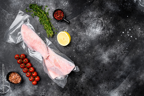 Perch frozen fish meat pack , with herbs, on black dark stone table background, top view flat lay, with copy space for text photo