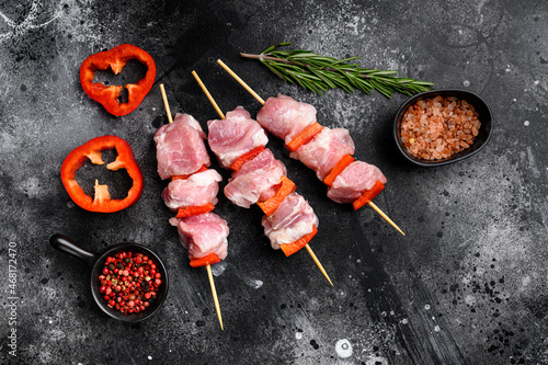 Raw pork shish kebab. BBQ meat with vegetables, top view flat lay, with copy space for text, on black dark stone table background