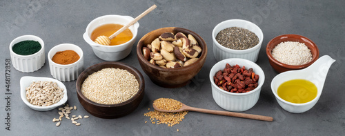 Assorted superfoods in spoons over stone background. Chia, quinoa, oat, linseed, honey, spirulina and others