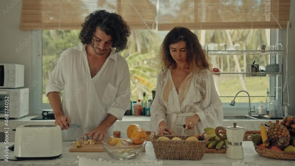 Young happy active married couple dancing laughing together cooking meals at home, carefree joyful husband and wife have fun cooking healthy breakfast food in boho styled kitchen Young happy active married couple dancing laughing together cooking meals at home, carefree joyful husband and wife have fun cooking healthy breakfast food in boho styled kitchen