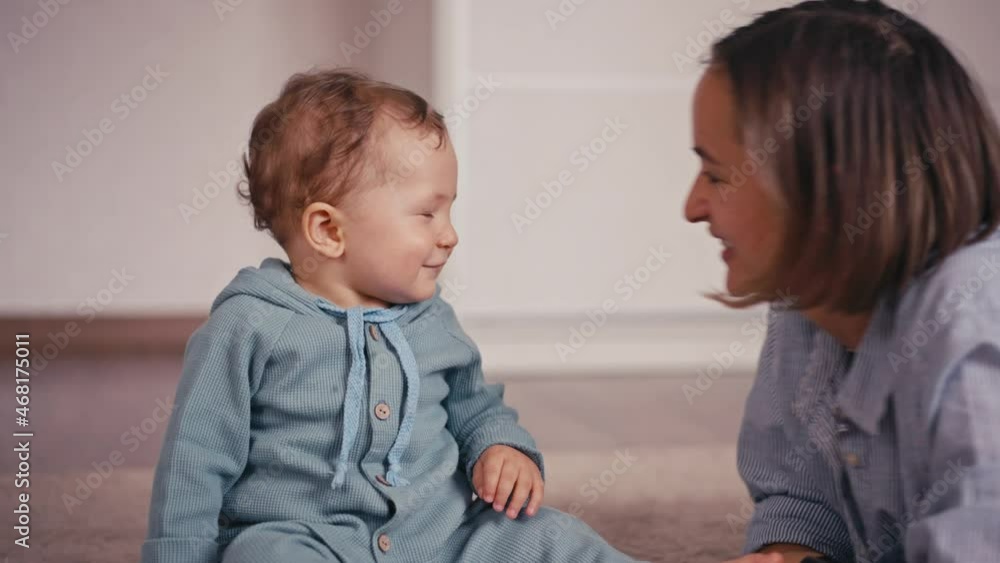 Mother and her baby son having fun and playing at home. Little kid 1 years old play with his mom at home sitting on the floor. They feel happy, smile and laugh Mother and her baby son having fun and playing at home. Little kid 1 years old play with his mom at home sitting on the floor. They feel happy, smile and laugh