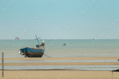 fisherman's fishing boat on sand at a fishing village beach There is an island and sea background with the daytime sky.  stranded fishing boat After the sea has receded