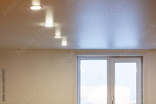 White light bulbs on the stretch ceiling by the window