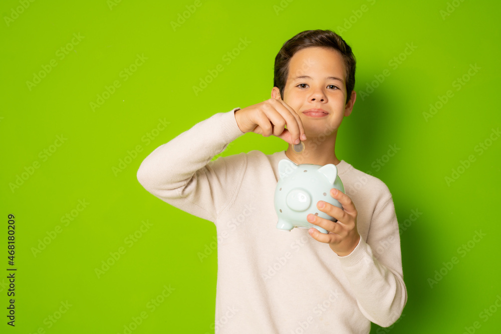 Child boy holding piggy bank isolated over green background. Child boy holding piggy bank isolated over green background.