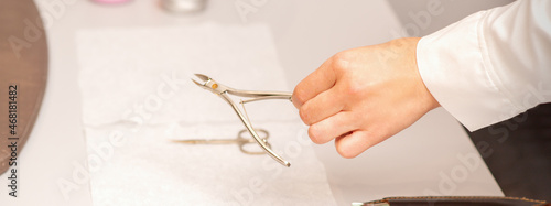 Nail nippers in the hand of female manicure master putting to the towel before nail care in manicure salon