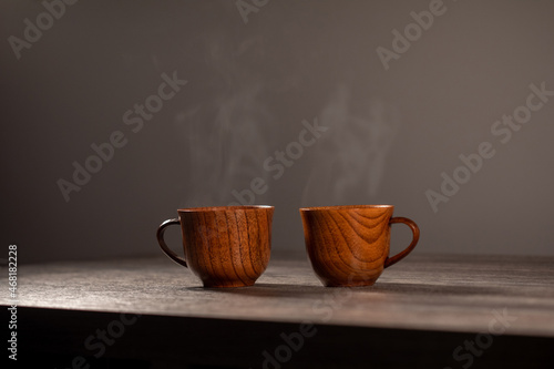 Wooden mug with coffee. Steam comes from the cup from hot coffee, chocolate, tea. Christmas lights in the background. Christmas is coming soon