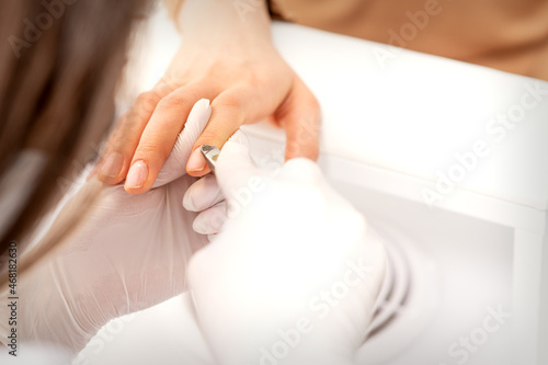Manicure master uses manicure clippers removing cuticles on female nails in a beauty salon close up