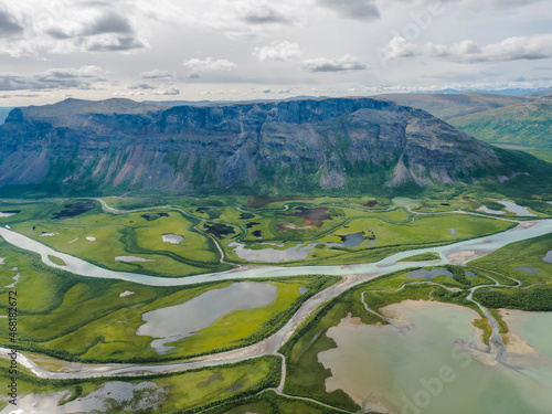 фотографія Aerial scenic view from Skierffe rock summit on glacial Rapadalen river delta valley at Sarek national park with meanders, lakes, mountains and birch trees