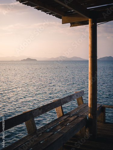 Fototapeta Naklejka Na Ścianę i Meble -  Scenic view of peaceful blue water bay with layer islands in evening before sunset from wooden pier pavilion foreground. Koh Mak Island, Trat Province, Thailand. Selective focused on sea.