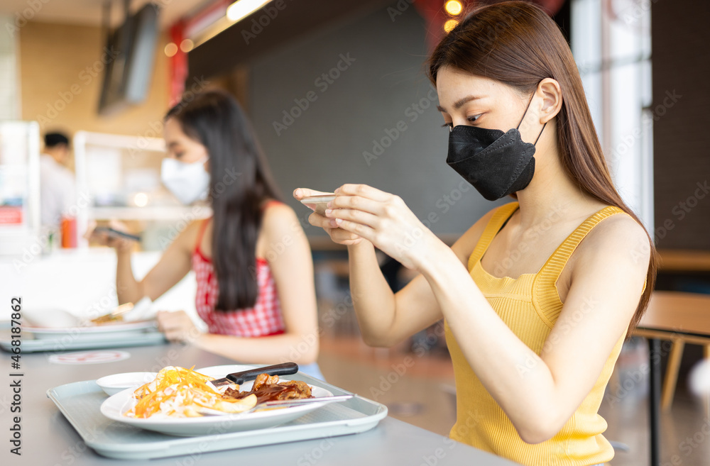 Young attractive asian teen female influencer, foodie blogger take photo of food  .keep social distance for protect infection from coronavirus covid-19, restaurant and social distancing concept.