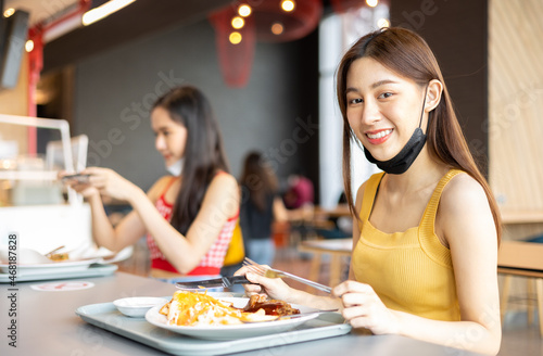 Asian woman sitting separated in restaurant eating food .keep social distance for protect infection from coronavirus covid-19  restaurant and social distancing concept.