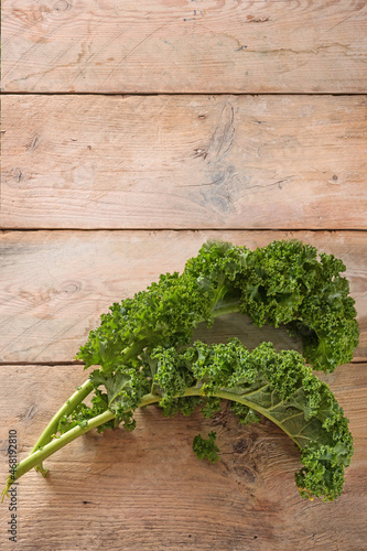 Curly leaves of kale or green leaf cabbage on rustic wooden planks, vertical format with large copy space for an announcement poster, copy space, top view from above
