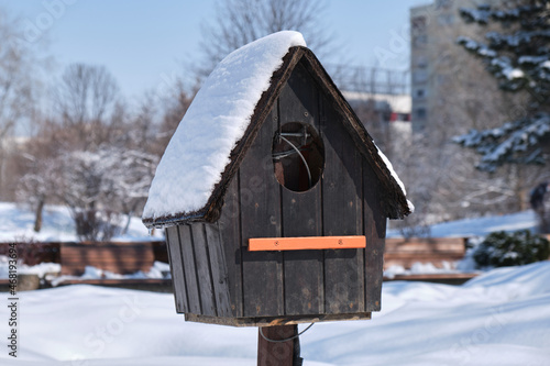 Empty bird house covered with fresh snow, on bright sunny Winter day. Close up.