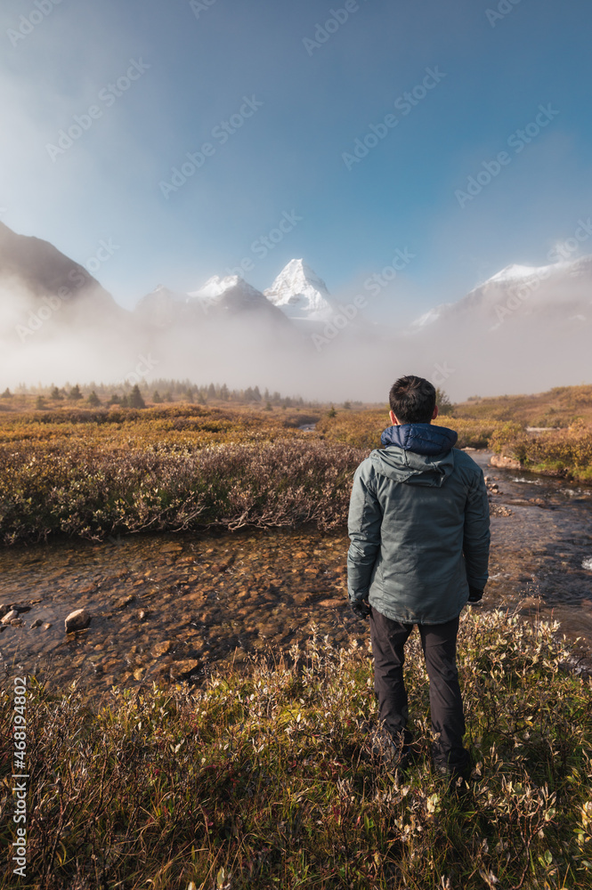 Traveler man standing and looking the mount Assiniboine in foggy on autumn forest at provincial park Traveler man standing and looking the mount Assiniboine in foggy on autumn forest at provincial park