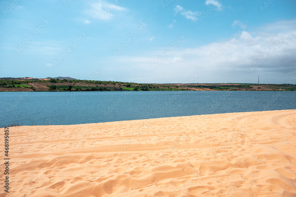 Desert dune and blue river on sunny day
