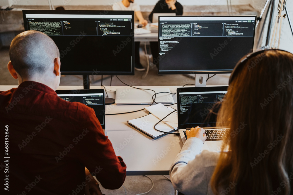 Male and female programmer doing coding over laptop in startup company Male and female programmer doing coding over laptop in startup company