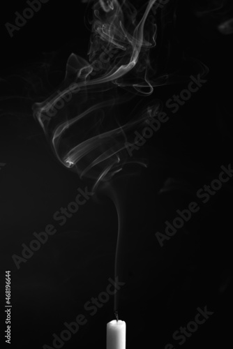 Schilderij op canvas Vertical shot of the smoke of an extinguished candle isolated on a black backgro