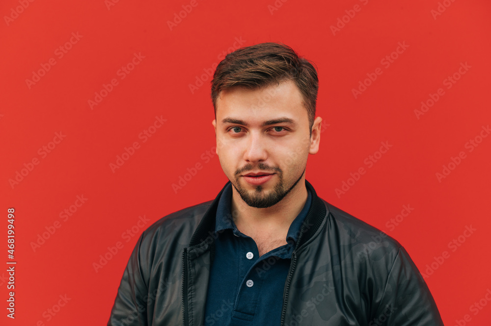 Portrait of handsome macho man with beard on red wall background, looking at camera with grin. Portrait of handsome macho man with beard on red wall background, looking at camera with grin.