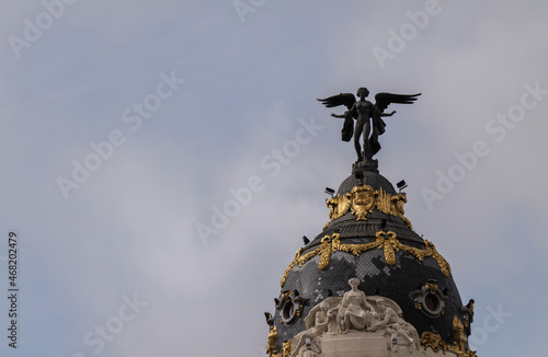 Angel statue on tower of Metropolis building in center of Madrid, Spain, against sky.