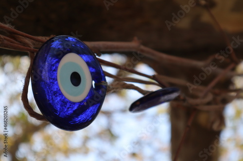 Nazar - traditional blue glass eye turkish amulet from the evil attached to the branches of a tree close up