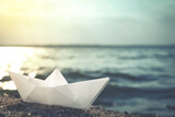 White paper boat near river on sunny day. Retro photo effect