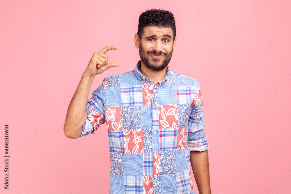 Too small amount! Portrait of disappointed man in blue casual style shirt showing a little bit gesture, dissatisfied with low rating, measuring scale. Indoor studio shot isolated on pink background. Too small amount! Portrait of disappointed man in blue casual style shirt showing a little bit gesture, dissatisfied with low rating, measuring scale. Indoor studio shot isolated on pink background.