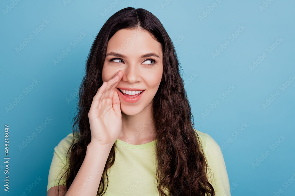 Photo of positive cunning lady hand open mouth tell secret look side empty space on blue background Photo of positive cunning lady hand open mouth tell secret look side empty space on blue background
