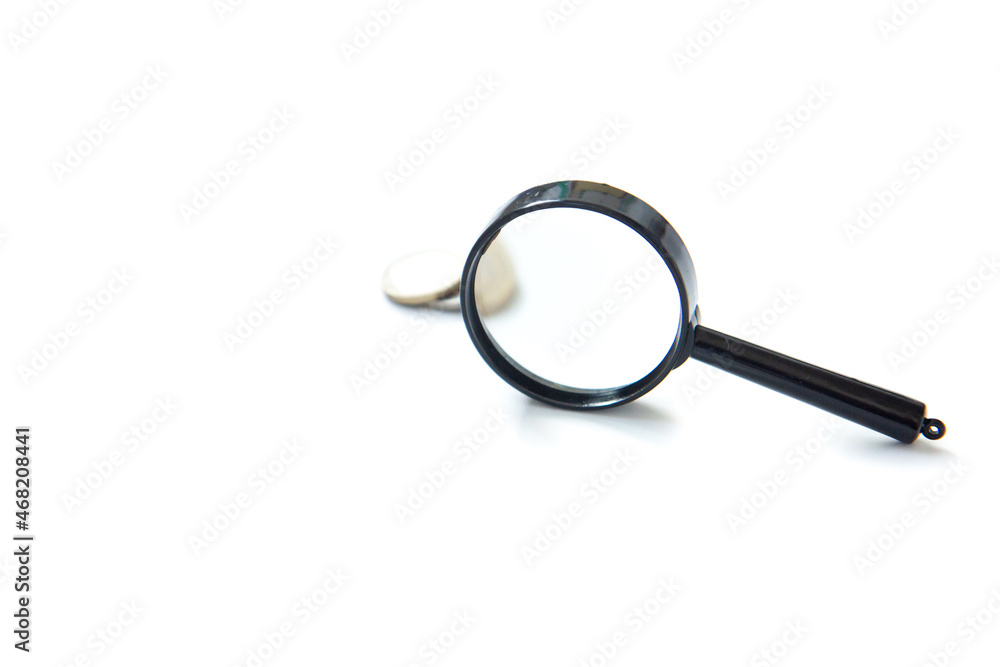 Magnifier and stack of coins isolated on white background. Concept of keeping money, investing Magnifier and stack of coins isolated on white background. Concept of keeping money, investing