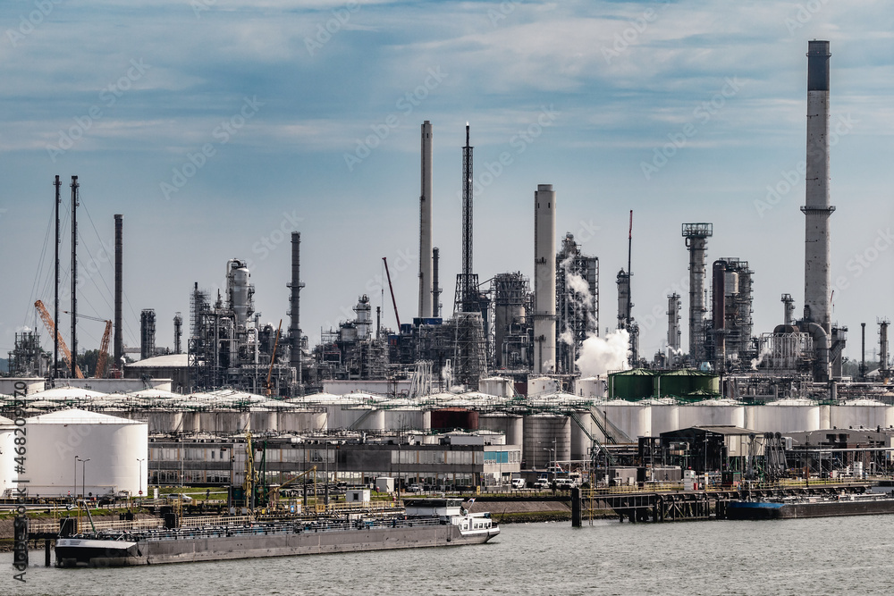 Oil refinery industrial petrochemical plant factory and barges in an industrial shipping port Oil refinery industrial petrochemical plant factory and barges in an industrial shipping port