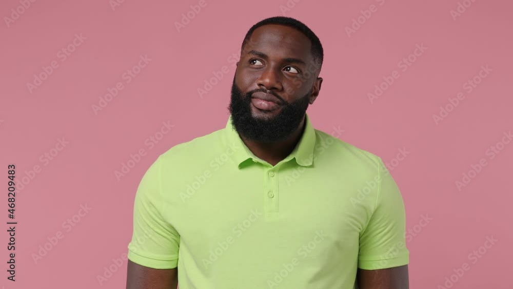 Dreamful pensive happy young bearded african american man 20s wears green t-shirtlook around think dream lost in thought and conjectures isolated on plain pastel light pink background studio portrait Dreamful pensive happy young bearded african american man 20s wears green t-shirtlook around think dream lost in thought and conjectures isolated on plain pastel light pink background studio portrait
