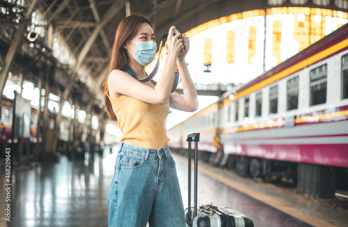 Asian backpack traveler people with camera standing at train station platform and waiting train arrivel  summer holiday travelling or young tourist concept