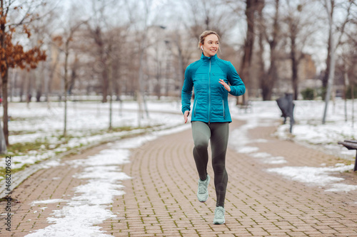 Fit sportswoman jogging on path in park on snowy winter day. Recreation, snowy weather, winter day © dusanpetkovic1